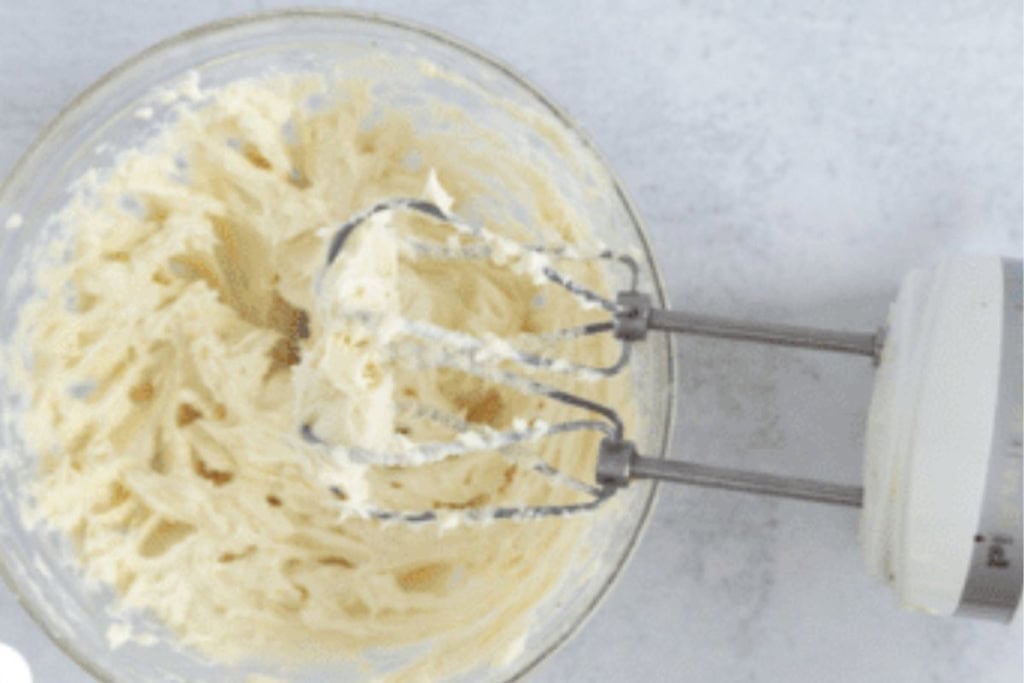 Cream cheese frosting in bowl with mixer.