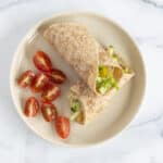 hummus wrap on plate with tomatoes