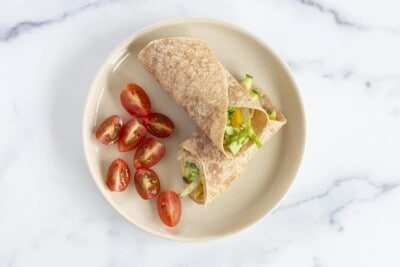 hummus wrap on plate with tomatoes