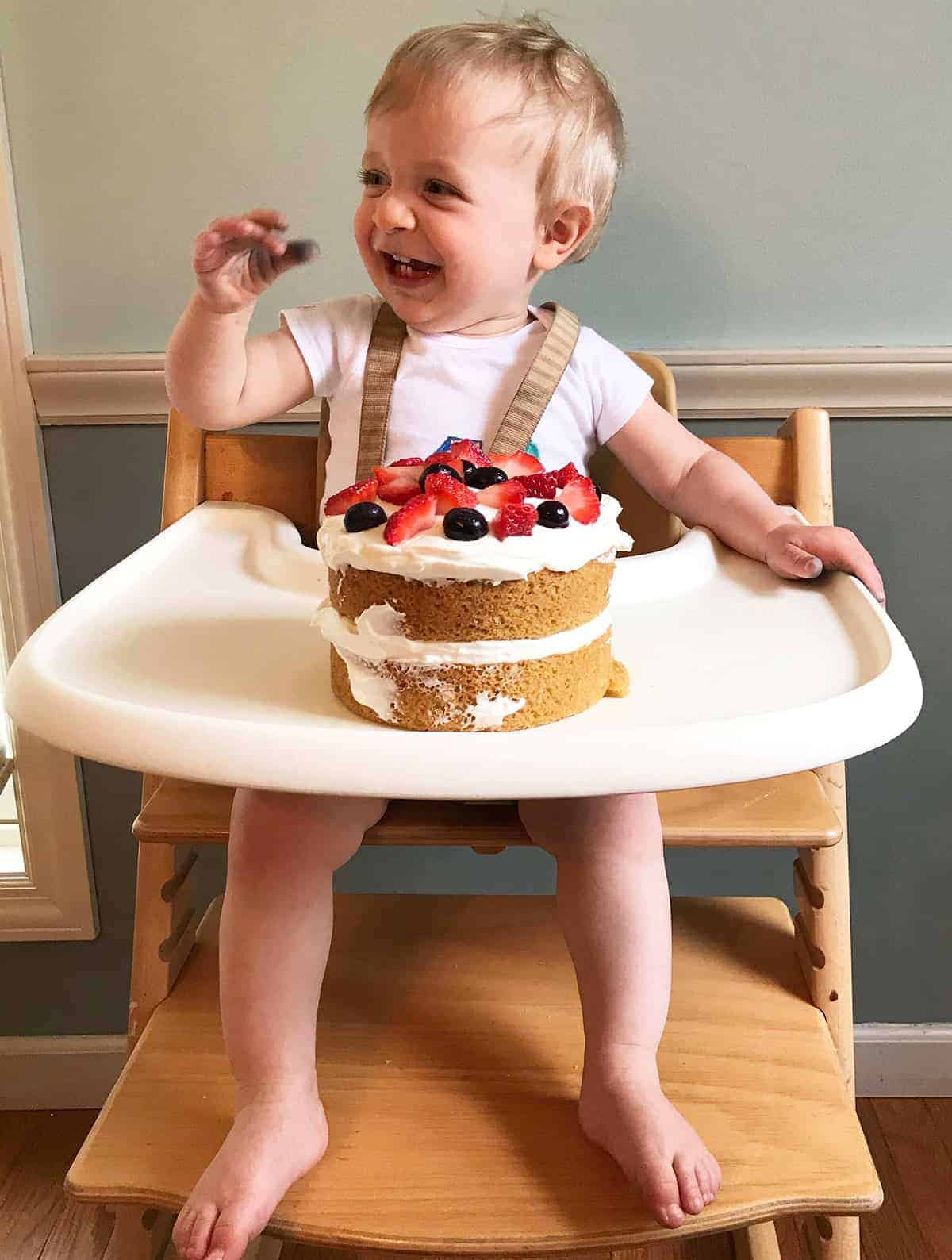 boy with first birthday smash cake on high chair tray.