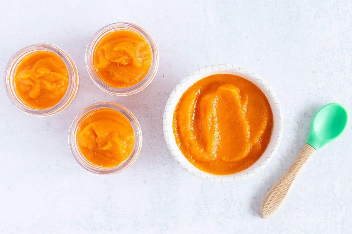 carrot baby food in containers with baby spoon