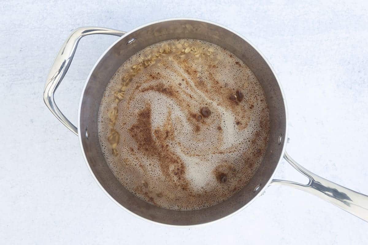 Oats, water, cinnamon, and vanilla in a cooking pot.