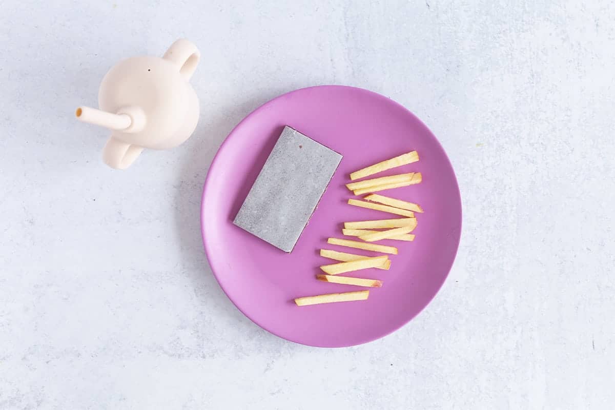 dino bar on kids plate with matchstick apple slices and pink cup