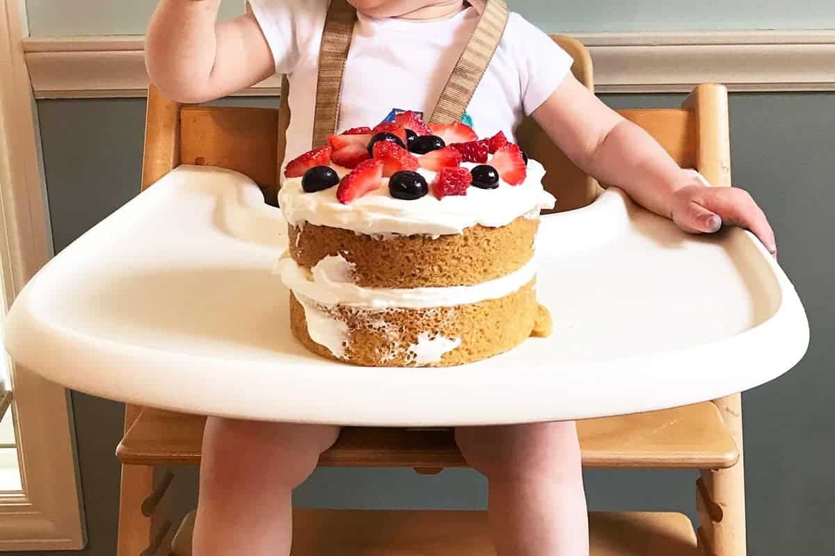 first birthday smash cake with berries on high chair tray.