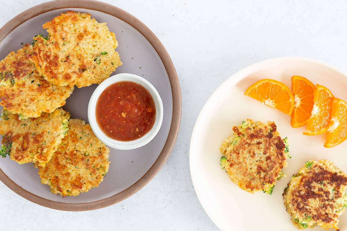 two plates of quinoa patties with oranges and dip.