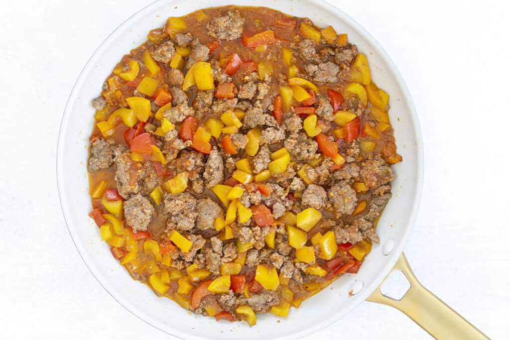 cooked unstuffed peppers in white skillet with tomatos.