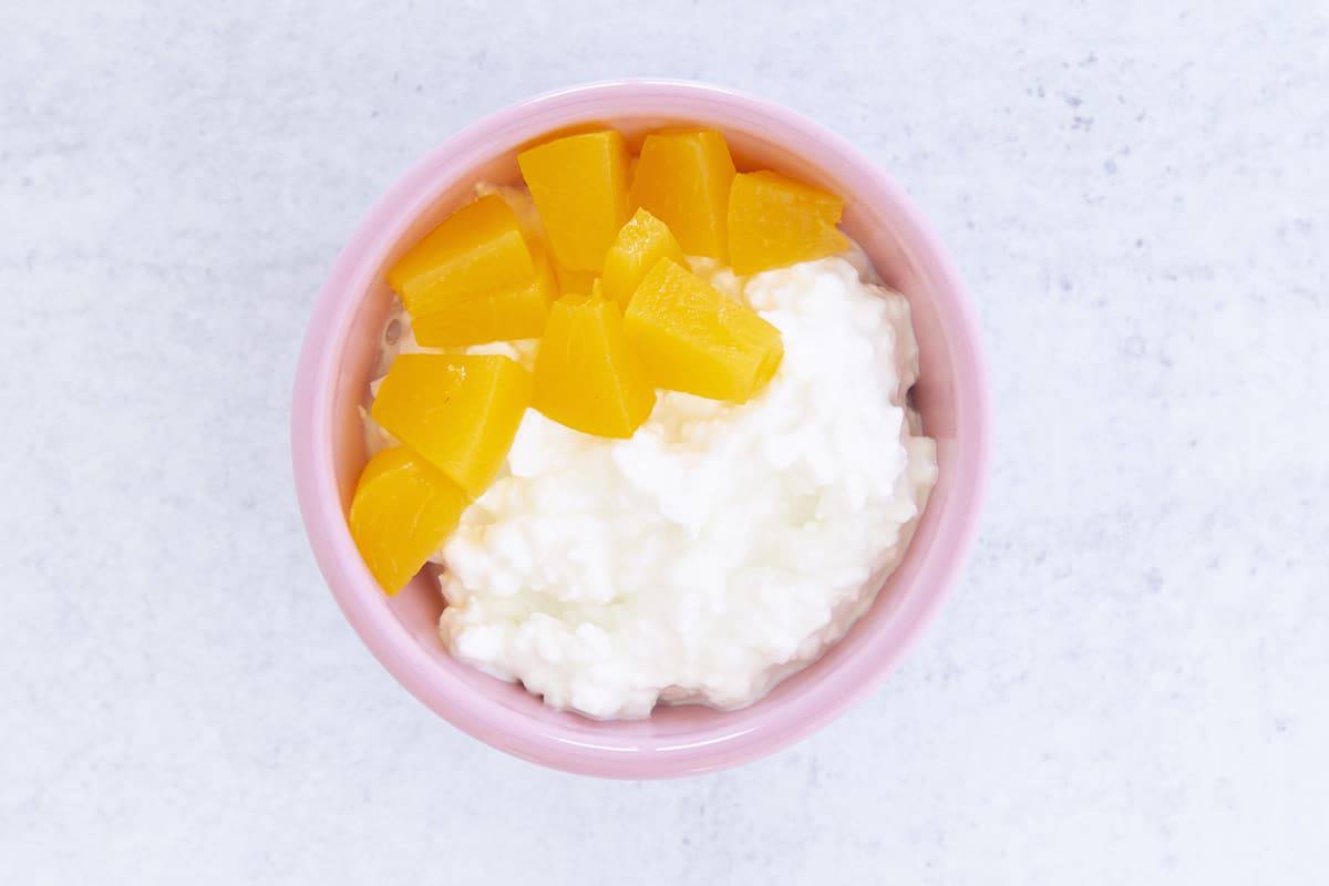 cottage cheese and diced peaches in pink bowl