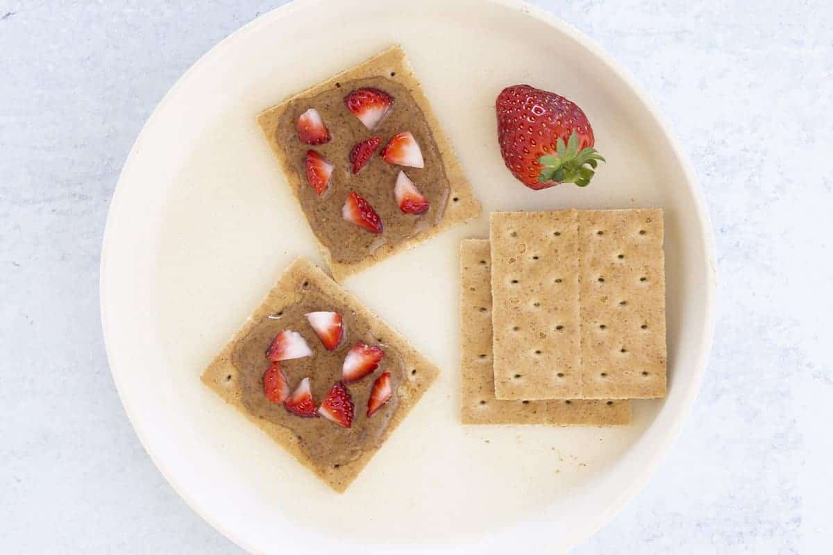 graham crackers with nut butter and berries on plate