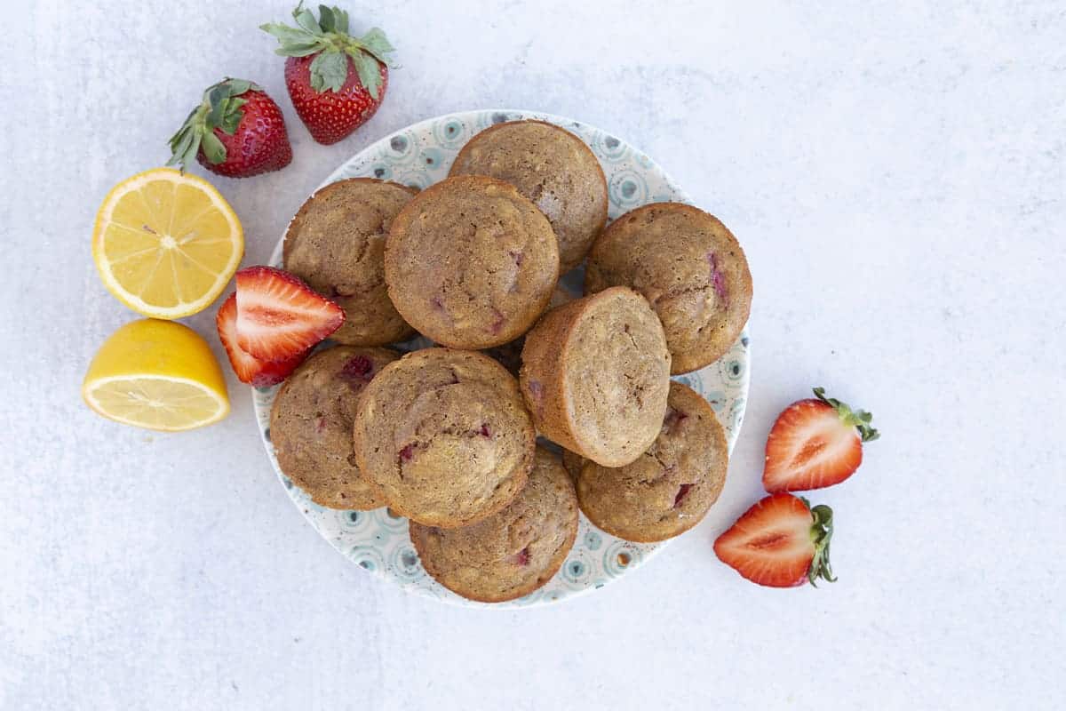 strawberry muffins on plate with berries and lemon.