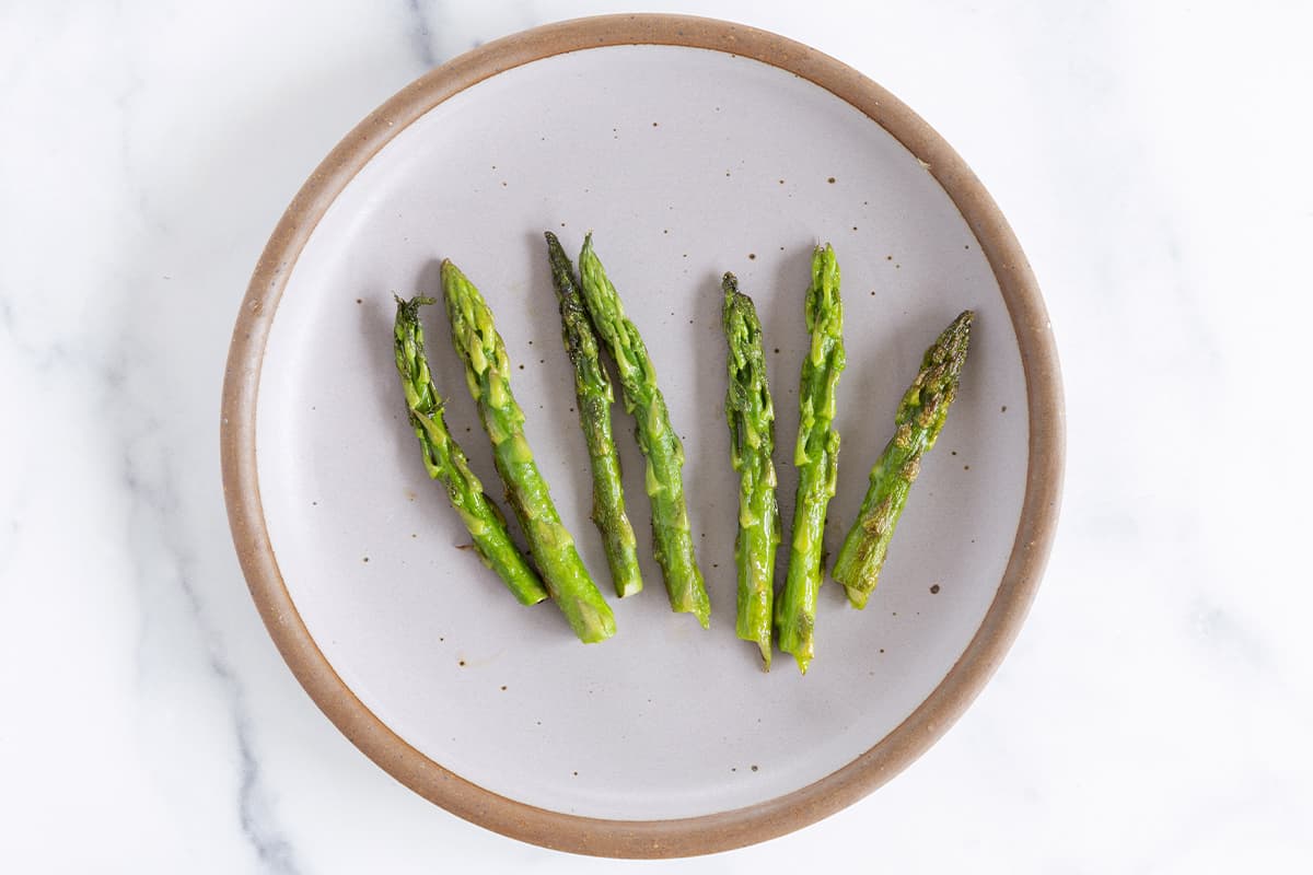 Cooked asparagus stalk heads on grey plate for baby led weaning