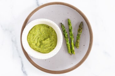 Pureed Asparagus baby food in bowl with cooked asparagus stalks on the side