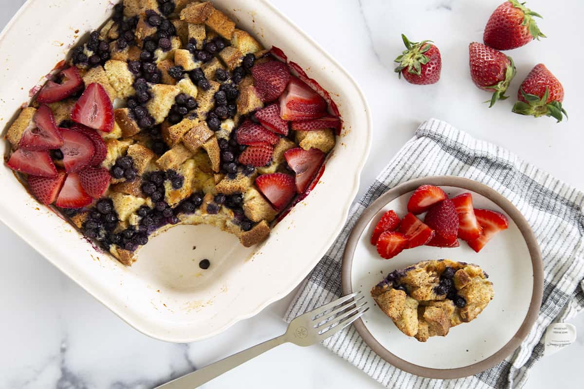 baked french toast casserole with spoonful on plate and side of strawberries