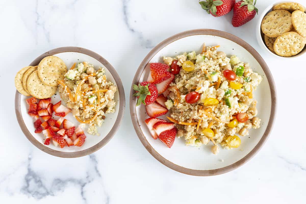 mediterranean quinoa salad on two plates with strawberries