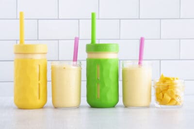 mango smoothie in cups lined up on counter