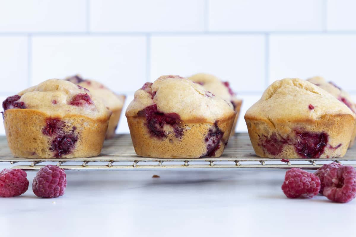 raspberry muffins on wire rack with berries.