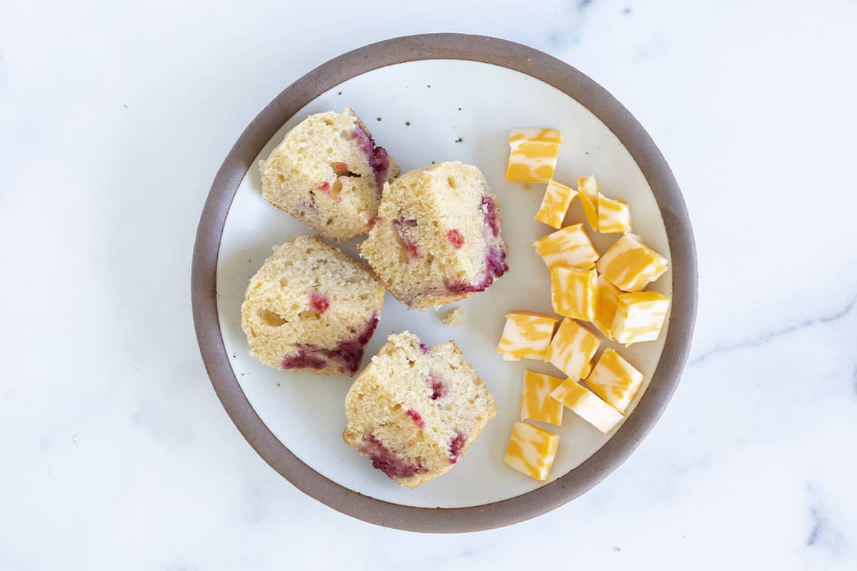 diced raspberry muffin on plate with cheese.