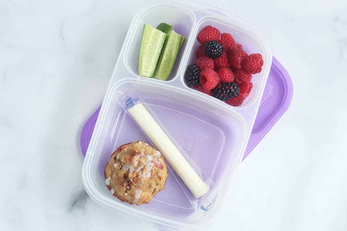 Strawberry muffin in container with sides for a vegetarian lunch idea.