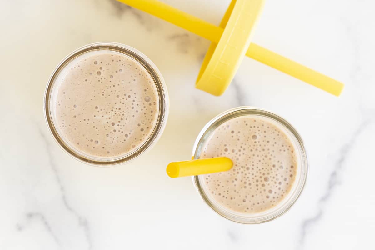 Chocolate weight gain smoothies in two glasses with straws overhead view
