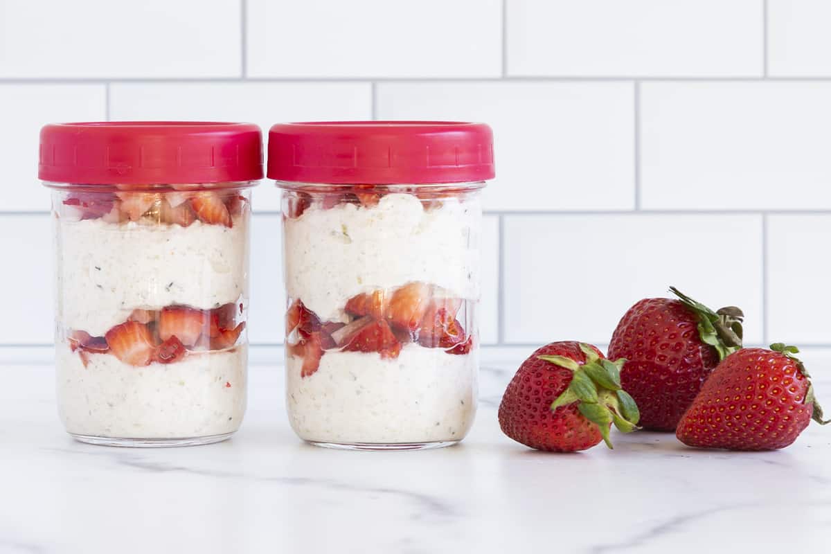 strawberry overnight oats in jars with red lids.