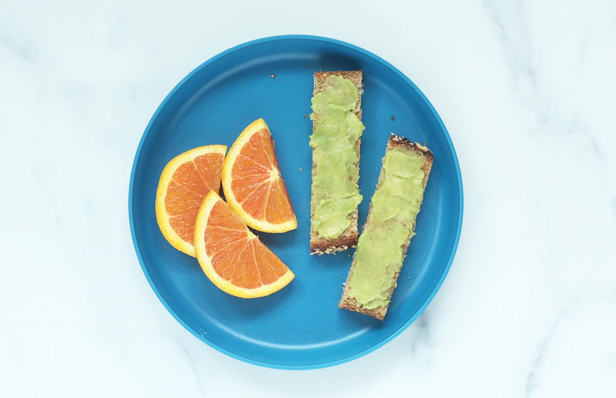avocado toast and orange slices on blue plate