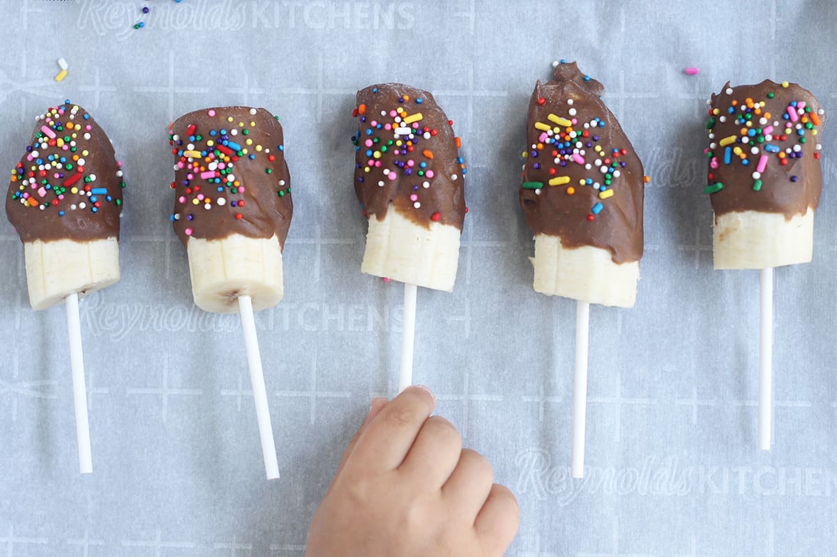 chocolate covered banana pops on parchment paper.