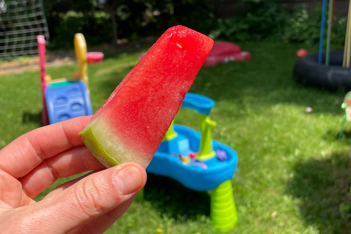 frozen stick of watermelon in hand.