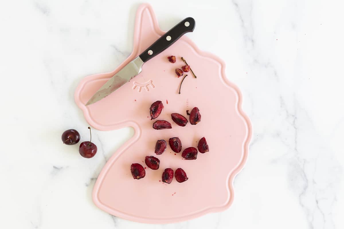 Cut cherries on pink unicorn cutting board
