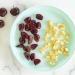 Cut cherries with pieces of cheese on blue plate