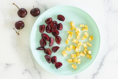 Cut cherries with pieces of cheese on blue plate