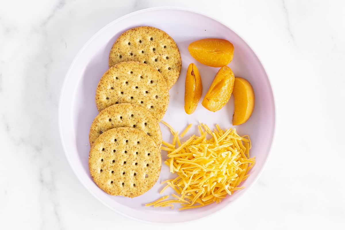 Crackers with cheese and fruit on plate