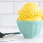 Mango sorbet in blue bowl on countertop with spoon