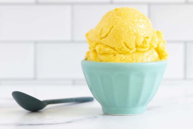 Mango sorbet in blue bowl on countertop with spoon