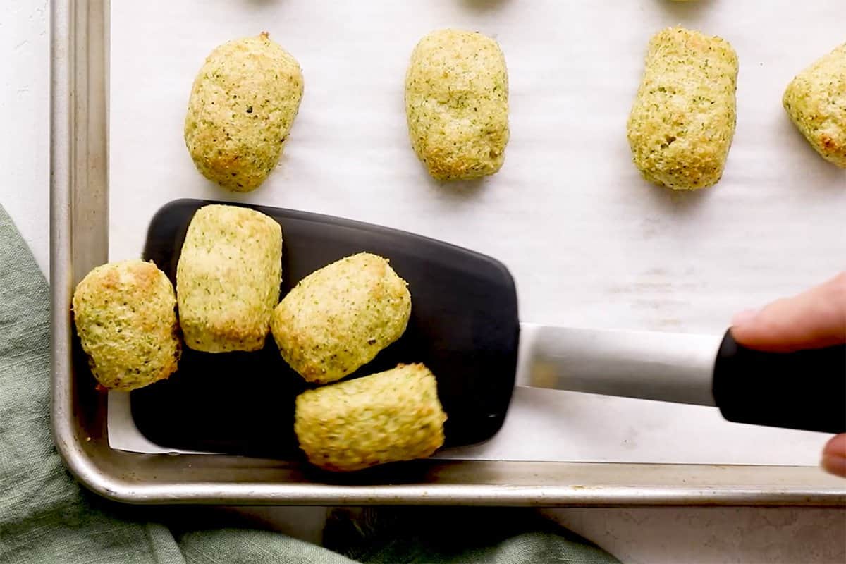 moving broccoli tots off baking sheet with spatula.