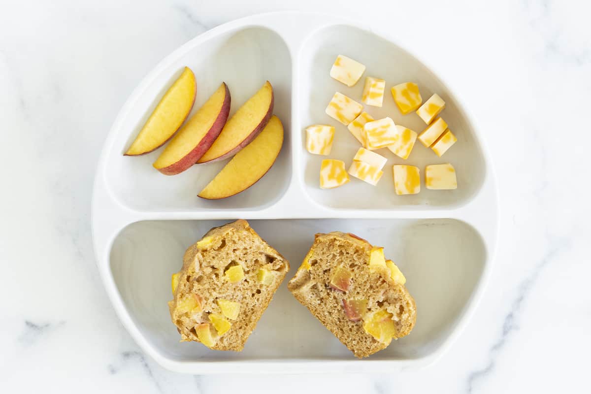peach muffins on toddler plate with slices mango and cubed cheese