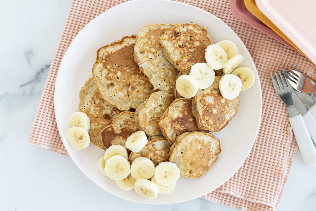 Oatmeal banana pancakes on plate with banana slices.