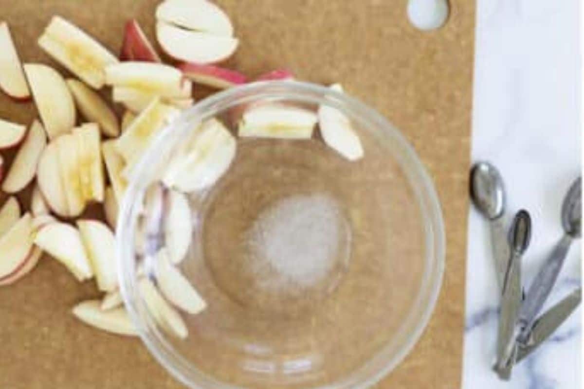Apple slices next to glass bowl. 