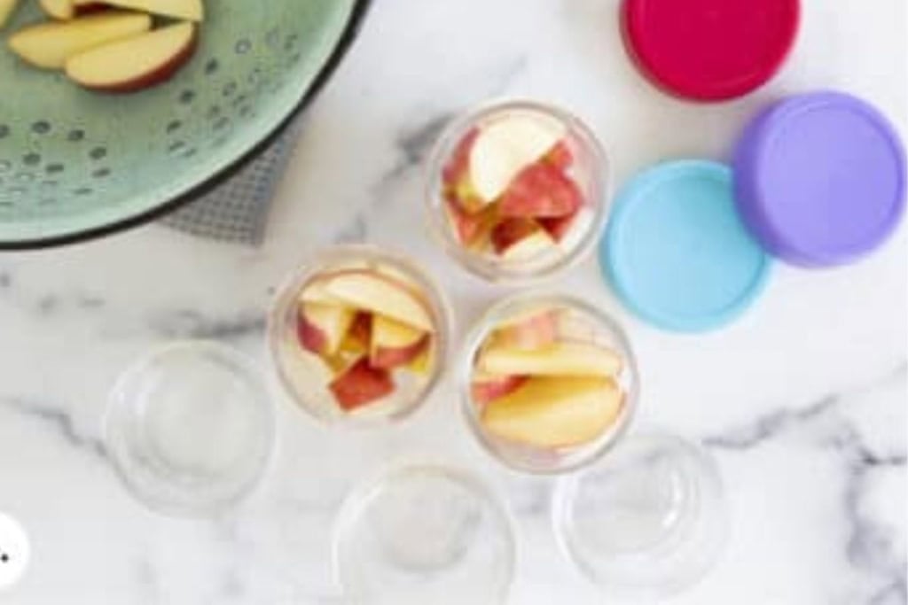 Apple slices being placed in storage containers.