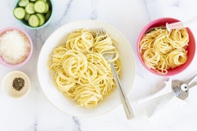 buttered noodles in two bowls with sides