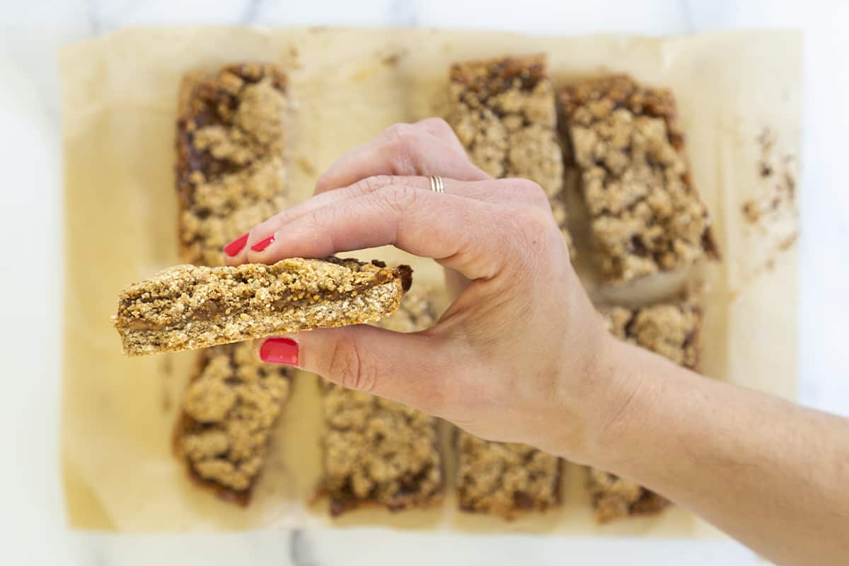 fig bars cut on parchment paper with hand holding bar