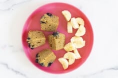 peanut butter muffin cut in quarters with banana on pink plate
