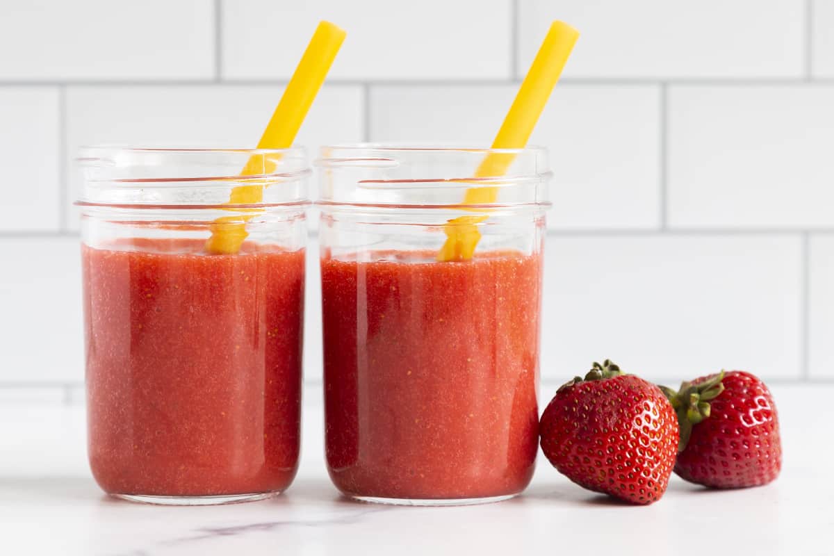 Strawberry juice in mason jars with yellow straws.