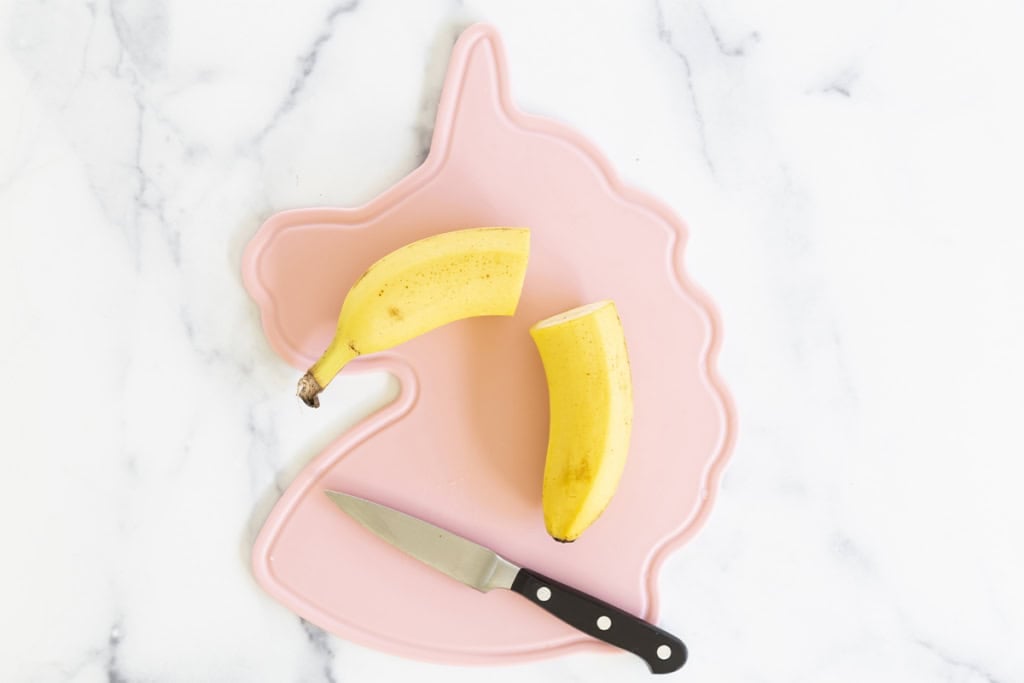 Banana cut in half on cutting board.
