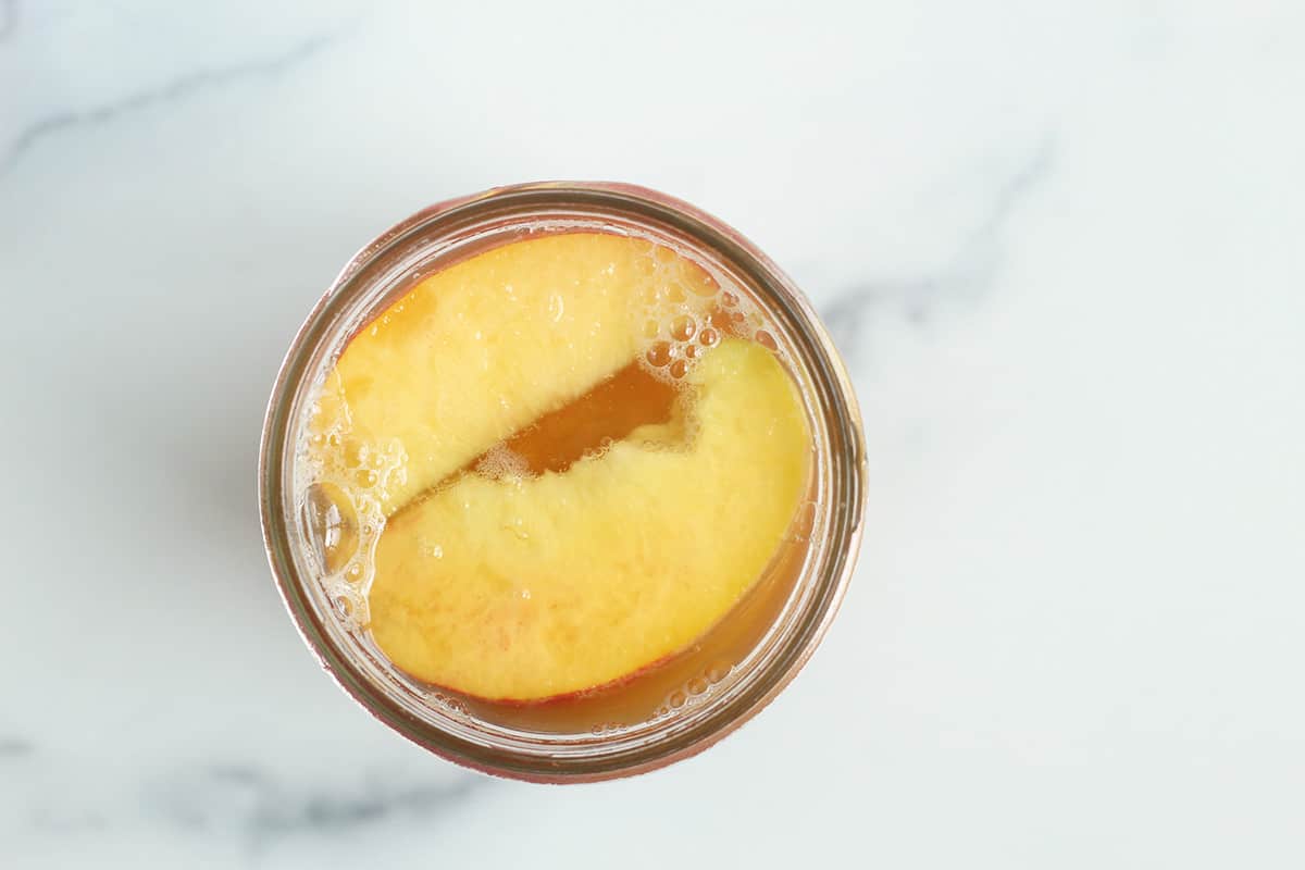 peaches in honey syrup in mason jar.