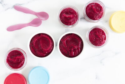 beets baby food in various containers with spoons and lids