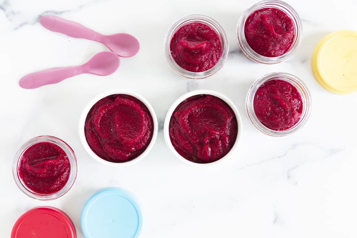 beets baby food in various containers with spoons and lids.