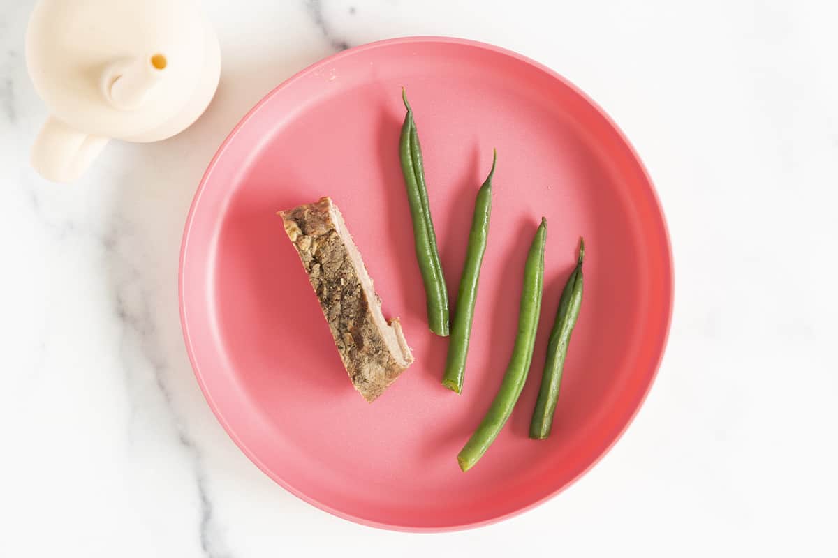Green beans on pink kids plate.