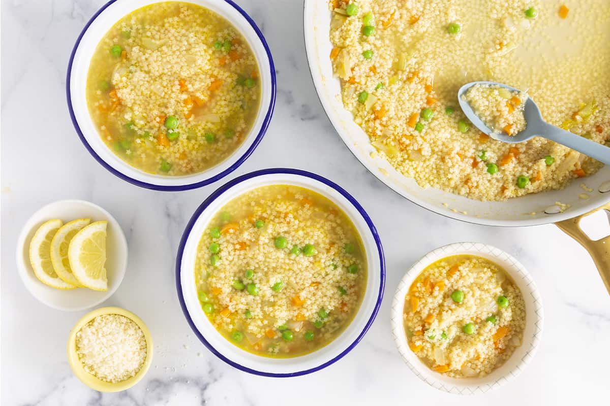 Pastina soup in numerous bowls with spoons and sides.