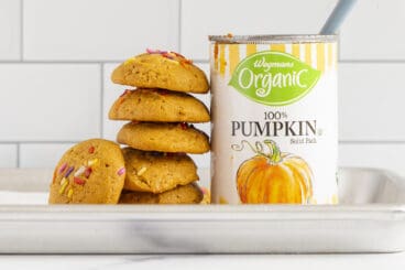 stack of pumpkin cookies with open can of pumpkin on counter.