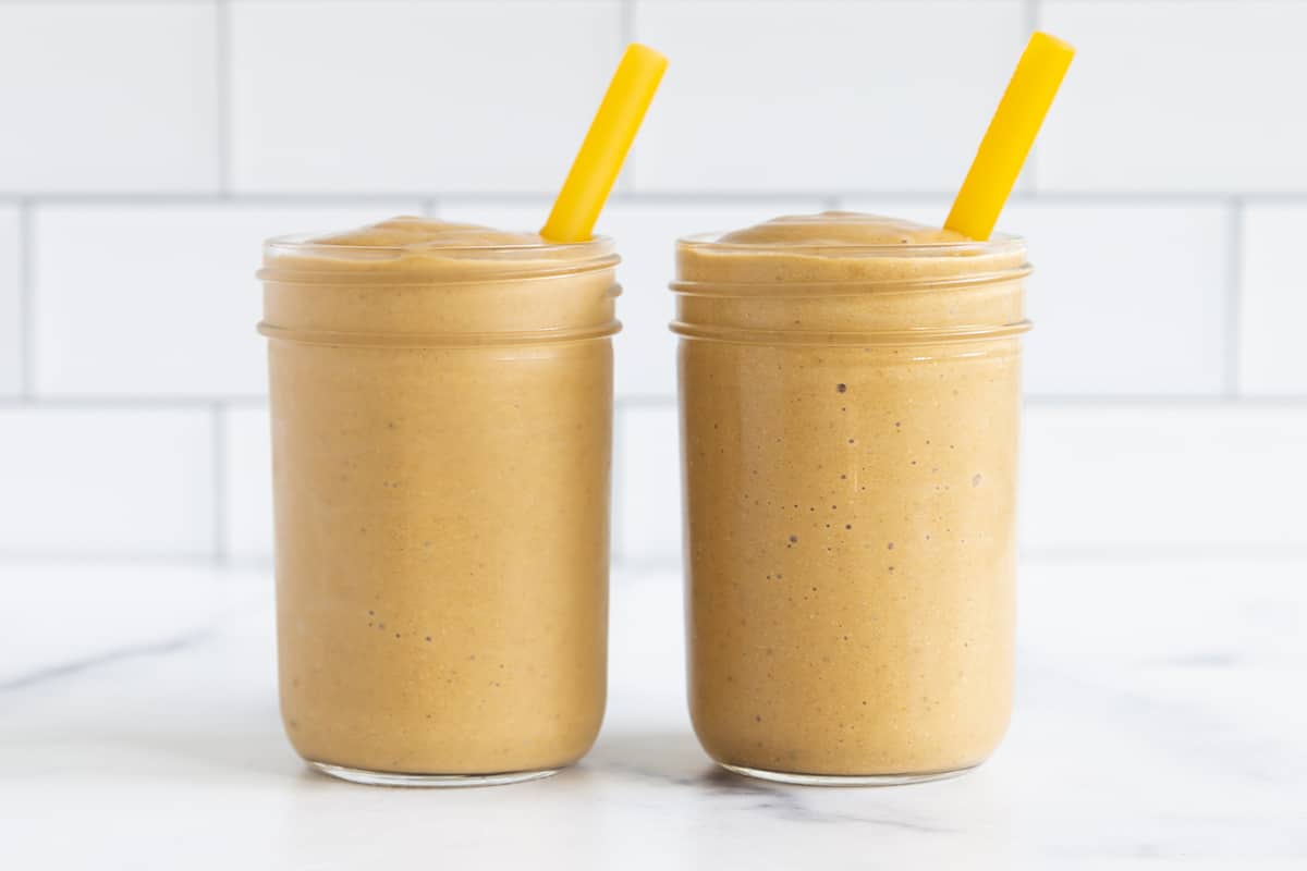 two cups of pumpkin smoothie with yellow straws.