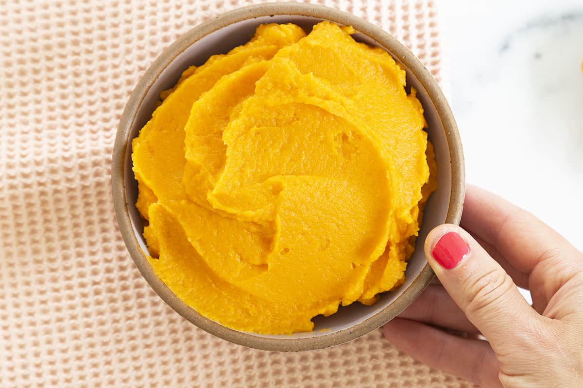 sweet potato puree in bowl with hand holding bowl